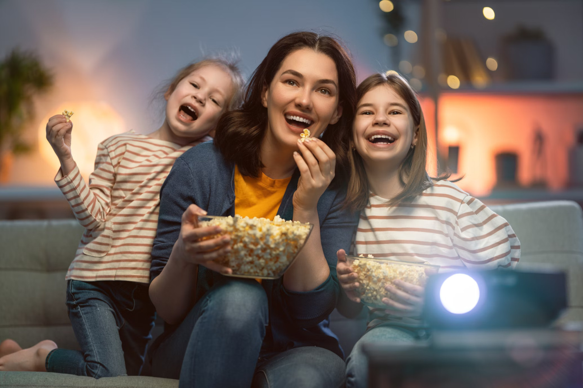 Mother and daughters enjoy watching movie and eating popcorn